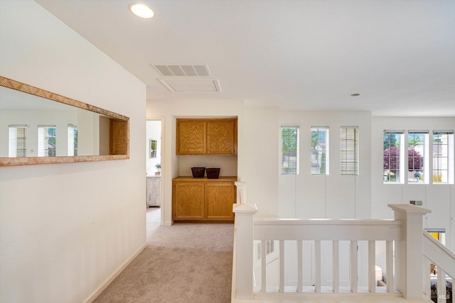 hallway with an upstairs landing, light carpet, baseboards, visible vents, and recessed lighting