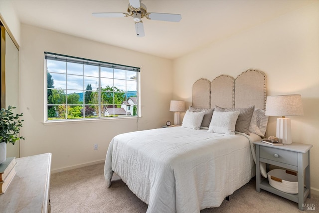 bedroom with ceiling fan, baseboards, and light carpet
