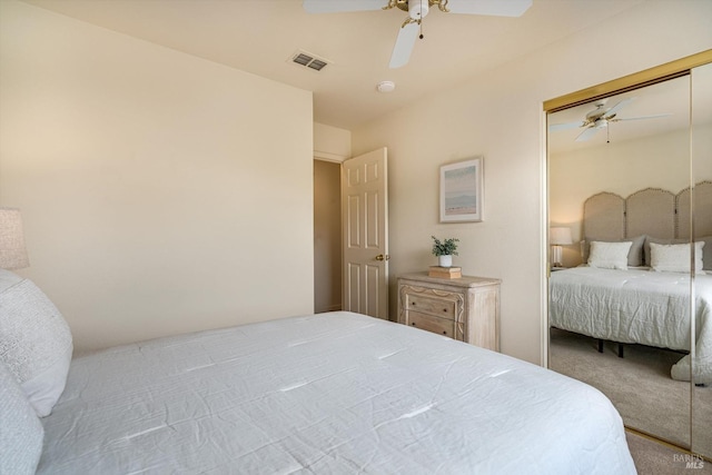 carpeted bedroom with a closet, visible vents, and ceiling fan