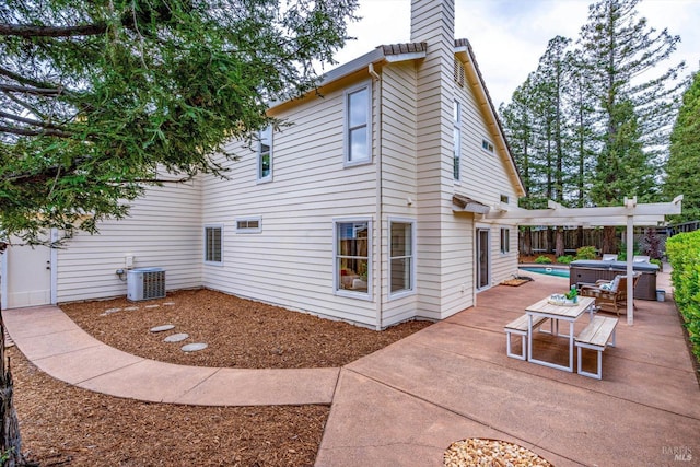 view of side of property featuring central AC unit, a patio area, a chimney, fence, and a hot tub