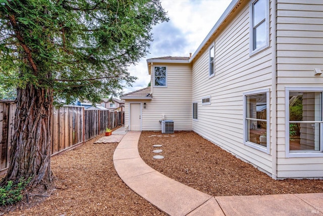 exterior space with a shingled roof, a fenced backyard, and central AC unit