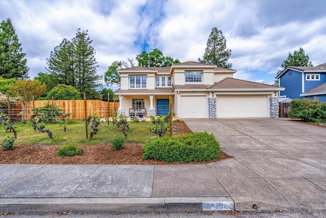 traditional-style house featuring an attached garage, driveway, stone siding, and fence
