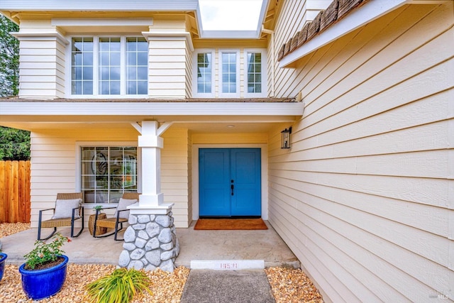 view of exterior entry featuring covered porch and fence