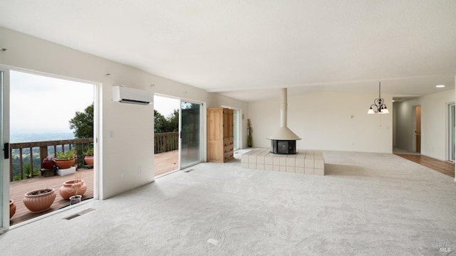 unfurnished living room featuring a wall unit AC, visible vents, an inviting chandelier, carpet floors, and a wood stove
