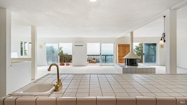 5750 Lichau Rd, Penngrove, CA 94951 - kitchen featuring tile countertops, open floor plan, a textured ceiling, a wall mounted air conditioner, and a wood stove