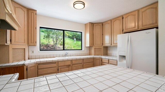 kitchen featuring light brown cabinetry, white refrigerator with ice dispenser, custom exhaust hood, and a sink