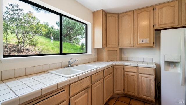 kitchen featuring light tile patterned flooring, a healthy amount of sunlight, white refrigerator with ice dispenser, and a sink