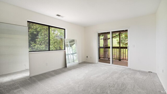 empty room featuring visible vents, carpet flooring, and a healthy amount of sunlight