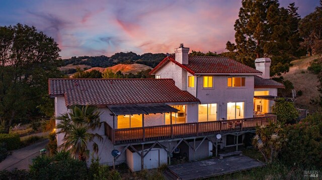 5750 Lichau Rd, Penngrove, CA 94951 - back of house at dusk featuring a chimney, a tile roof, stucco siding, and a wooden deck