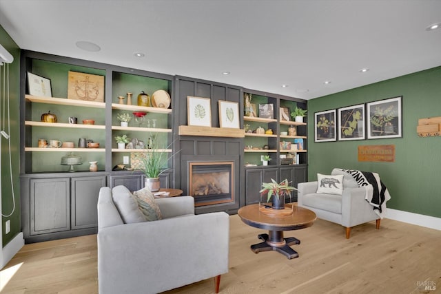 living room featuring a fireplace, light wood finished floors, baseboards, and recessed lighting
