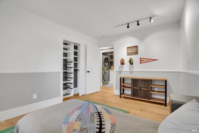bedroom featuring wood finished floors and stacked washer / dryer