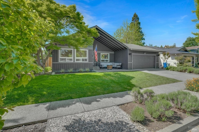 view of front facade with an attached garage, driveway, a front yard, and an outdoor living space