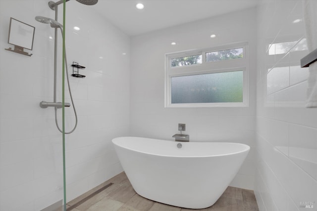bathroom with tile walls, a freestanding tub, recessed lighting, and a tile shower