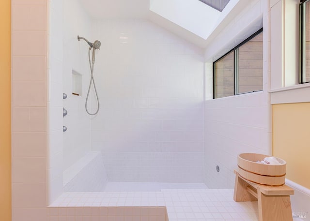 bathroom featuring lofted ceiling with skylight and tiled shower