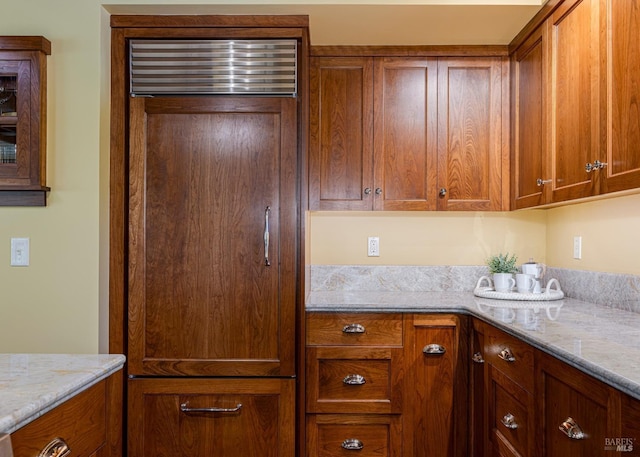kitchen with brown cabinetry and light stone counters