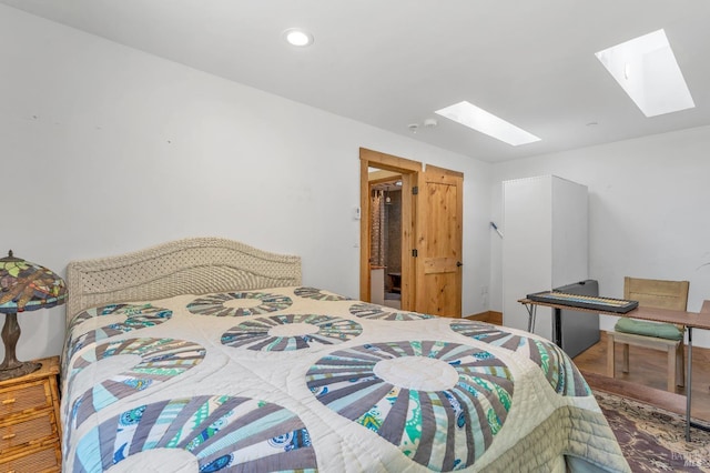 bedroom with recessed lighting, wood finished floors, and a skylight