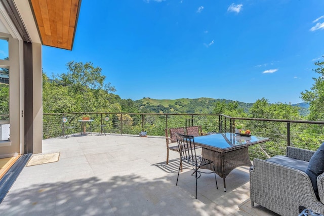 view of patio / terrace featuring a mountain view, outdoor dining area, and a forest view