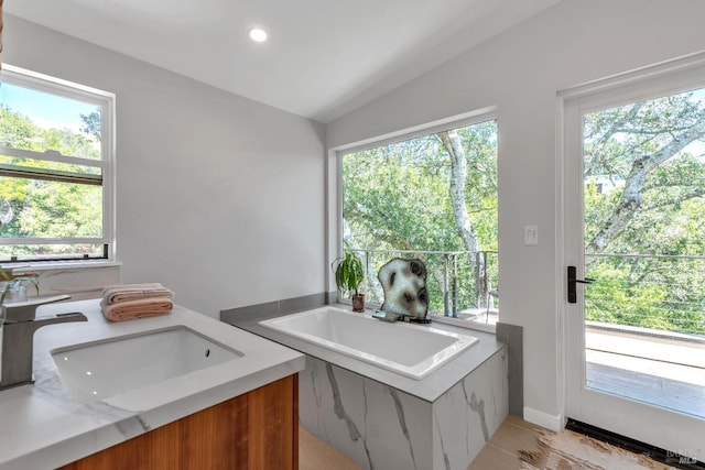 full bath with a sink, plenty of natural light, a bath, and lofted ceiling