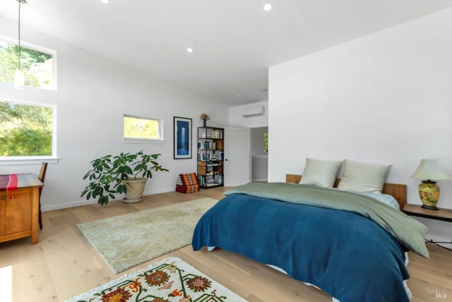 bedroom featuring baseboards, a wall mounted air conditioner, recessed lighting, and wood finished floors