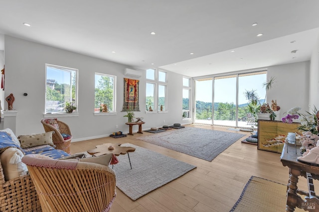 living area featuring recessed lighting, a wall mounted air conditioner, baseboards, and hardwood / wood-style floors