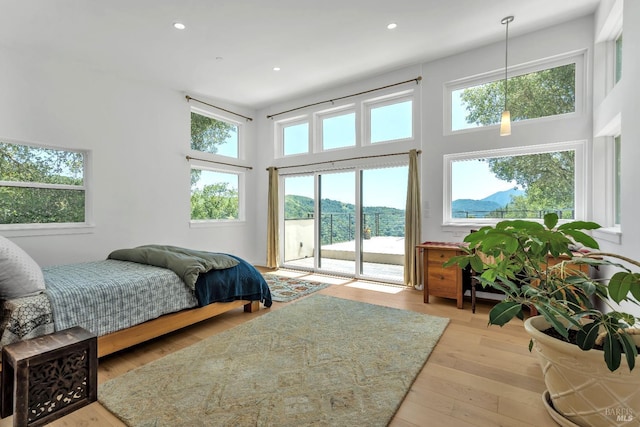 bedroom with recessed lighting, a high ceiling, access to exterior, and wood finished floors