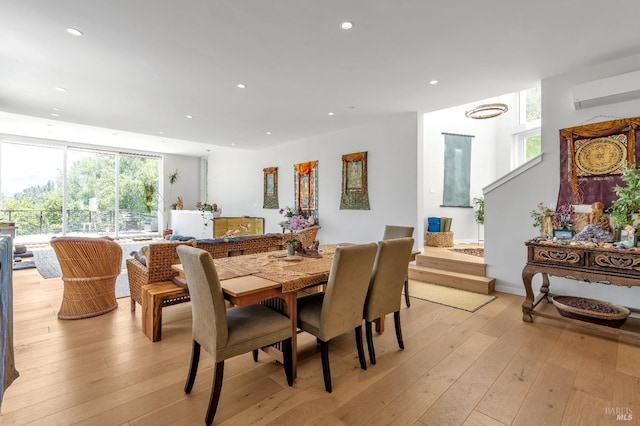 dining room with an AC wall unit, recessed lighting, and light wood-style flooring