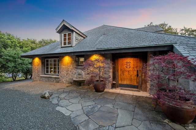 view of exterior entry with a high end roof and stone siding