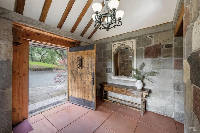 tiled foyer entrance featuring vaulted ceiling and a notable chandelier