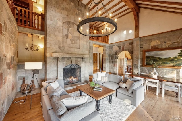 living area with hardwood / wood-style floors, beamed ceiling, arched walkways, a chandelier, and high vaulted ceiling