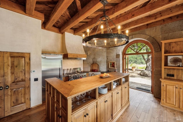 kitchen featuring premium appliances, beamed ceiling, premium range hood, wood counters, and light wood-style flooring