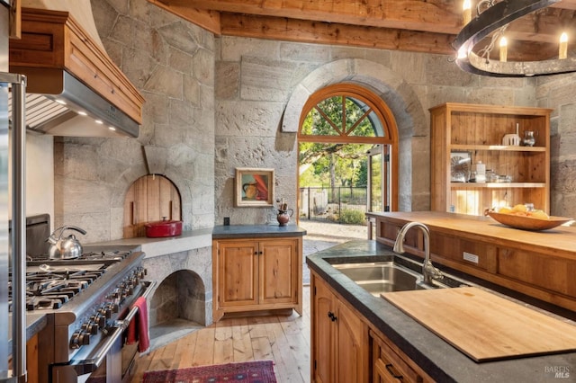 kitchen with light wood-type flooring, custom range hood, a sink, and range with two ovens