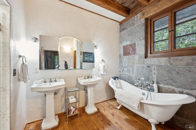 full bathroom featuring beamed ceiling, a freestanding tub, a sink, and wood-type flooring