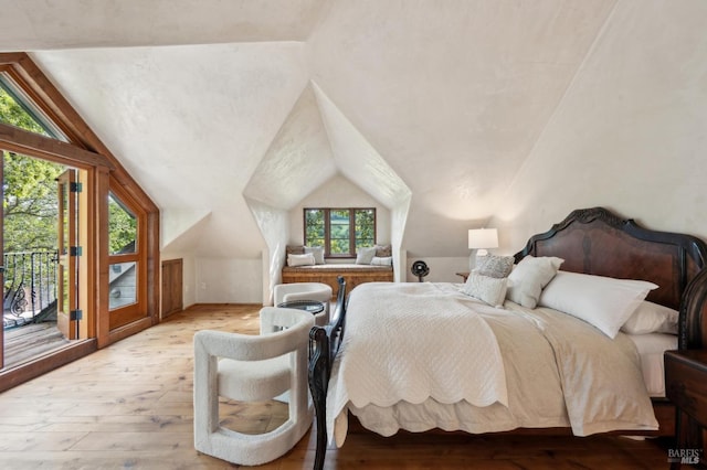 bedroom featuring lofted ceiling, access to exterior, and hardwood / wood-style floors
