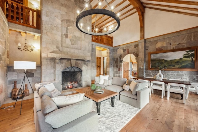 living area with arched walkways, beam ceiling, an inviting chandelier, hardwood / wood-style flooring, and high vaulted ceiling