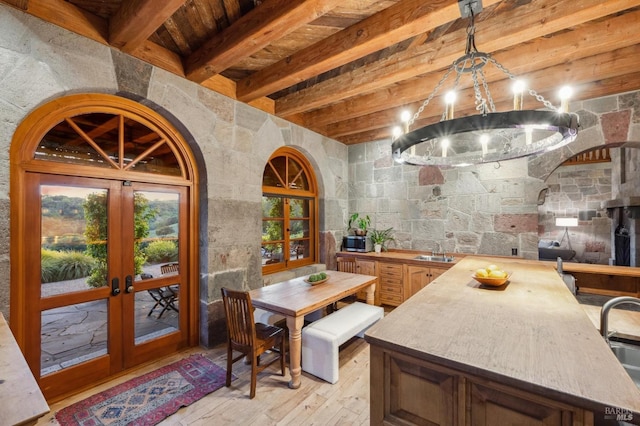 interior space featuring wooden counters, french doors, beamed ceiling, light wood-style floors, and a sink