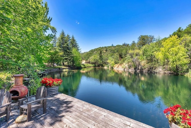 view of dock with a forest view and a water view