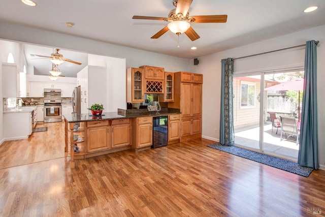kitchen with beverage cooler, under cabinet range hood, stainless steel appliances, a ceiling fan, and light wood-style flooring