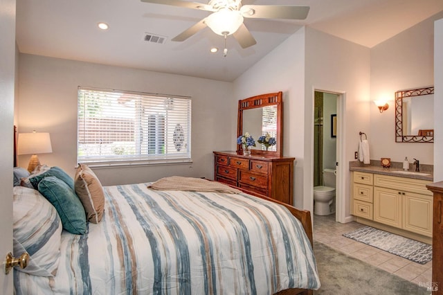 bedroom with a sink, light tile patterned flooring, vaulted ceiling, visible vents, and ensuite bath