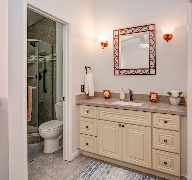 bathroom with tile patterned flooring, vanity, a stall shower, and toilet