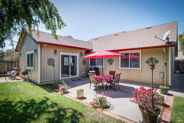 back of property with fence, a yard, a patio, and a shingled roof