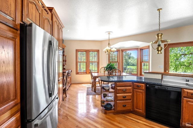 kitchen featuring brown cabinets, light wood finished floors, a notable chandelier, black dishwasher, and freestanding refrigerator