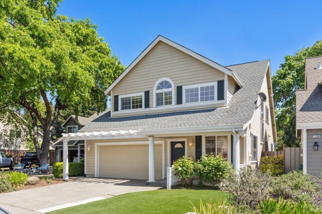 traditional-style house with fence, a shingled roof, driveway, and a garage