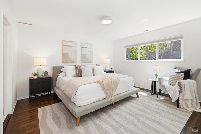 bedroom with wood finished floors, visible vents, and baseboards