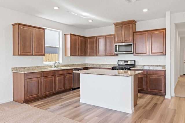 kitchen featuring stainless steel appliances, a center island, a sink, recessed lighting, and light wood-style floors
