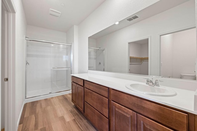 full bathroom with toilet, visible vents, wood finished floors, a shower stall, and vanity