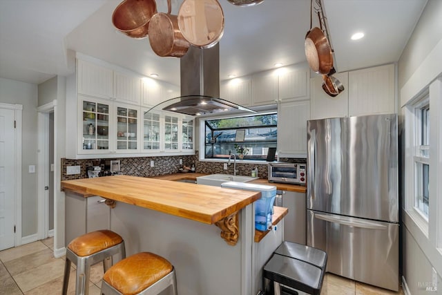 1416 F St, Napa, CA 94559 - kitchen with freestanding refrigerator, butcher block countertops, backsplash, a kitchen breakfast bar, and white cabinetry