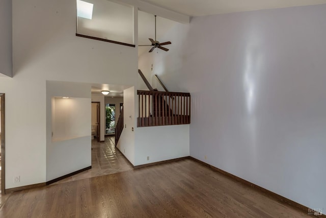 interior space featuring baseboards, a ceiling fan, wood finished floors, and high vaulted ceiling