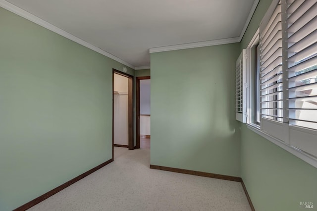 empty room featuring baseboards and crown molding