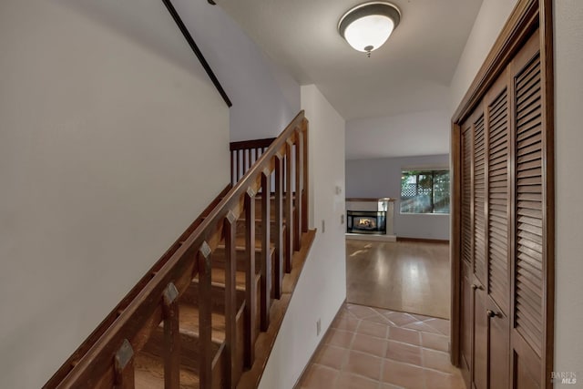 stairs with a glass covered fireplace and tile patterned flooring