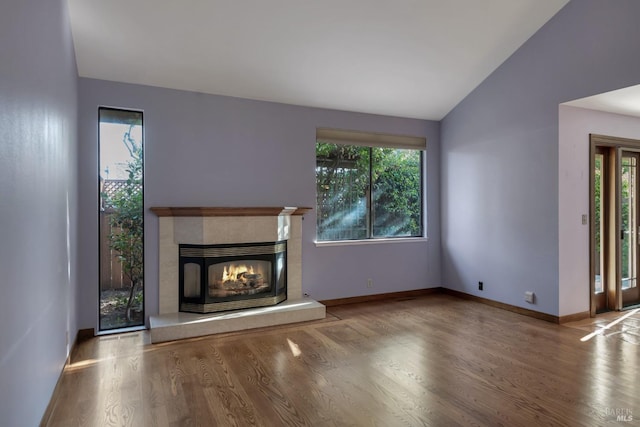 unfurnished living room featuring a fireplace, vaulted ceiling, baseboards, and wood finished floors